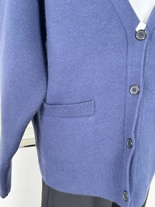 Close-up of blue knit cardigan featuring a V-neck, single-breasted buttons, and side pockets
