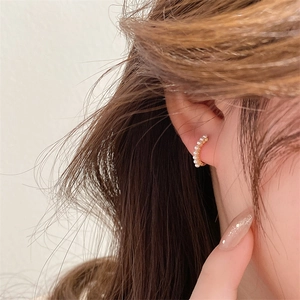 Detailed macro view of gold minimalist pearl earrings worn on ear showing sleek metal finish