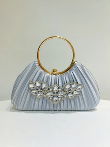 Detailed macro of silvery-blue pleated silk fabric with crystal flower and gold ring handle