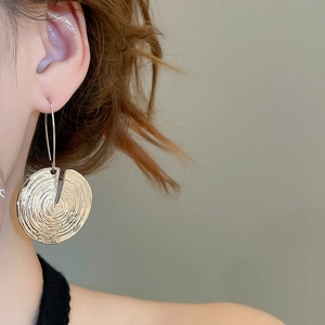 Close-up of golden textured circular hoop earrings worn by a model in a fashion style