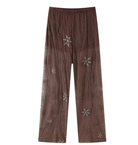 Gros plan détaillé du pantalon marron en tulle transparent avec broderie d'étoiles pailletées