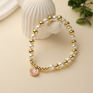 Detail of beaded bracelet with gold beads, pearls and pink moon enamel pendant charm