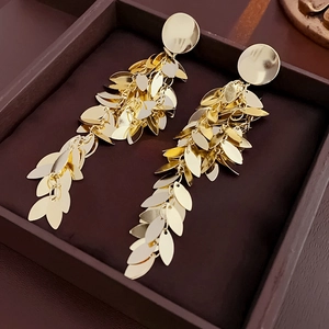 Macro shot of gold leaf tassel earrings with multi-layered metallic sequins in a gift box