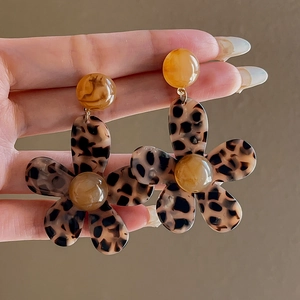 Close-up of retro leopard print flower earrings with amber bead detail and resin texture
