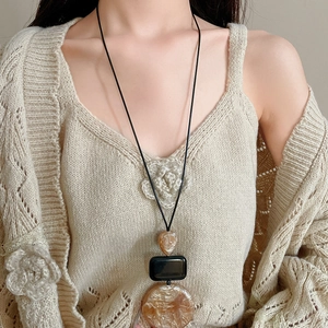 Close-up of geometric resin pendant necklace on model with amber and black details