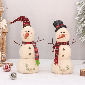 Pair of festive snowman plush ornaments with knit hats and scarves in a cozy Christmas setting