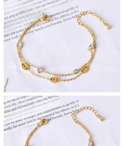 Detail of double-layer gold chain bracelet with evil eye charms and heart zircon stones