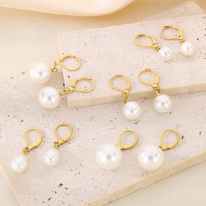 Dettaglio di orecchini di perle in acciaio placcato oro 18K su tessuto di seta beige