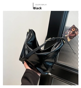Detail of glossy black hobo bag showing wrinkled texture leather and metal buckle strap