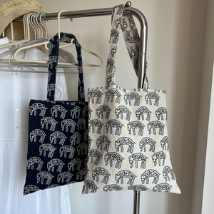 Close-up of navy and cream canvas tote bags with artistic animal embroidery patterns
