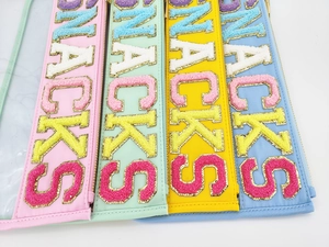 Close-up of snack bags with colorful chenille letter embroidery and gold metal zippers
