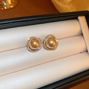 Gros plan de boucles d'oreilles perles dorées avec halo de zircon dans un écrin cadeau