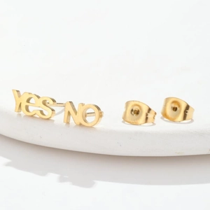 Flat lay of gold stainless steel stud earrings featuring YES and NO letter designs