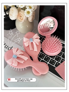 Detailliertes Set aus rosa Haarbürsten mit Schleife, Massagebürste und faltbarem Spiegel