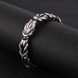 Close-up of vintage stainless steel knot bracelet with woven metal texture on a stand