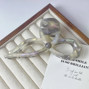Gros plan sur une grande pince à cheveux en acétate marbré dans un coffret à bijoux