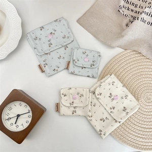 Detailed view of floral cotton storage pouches with snap button closure in a lifestyle setting