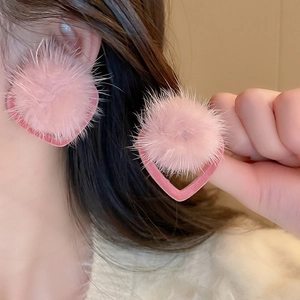 Close-up of pink fuzzy heart earrings with plush fur texture on female model's ear