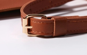 Macro shot of brown leather phone bag strap featuring adjustable golden metal buckle