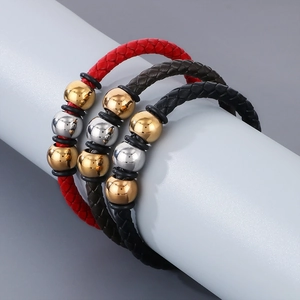 Close-up of stacked red, brown and black braided leather bracelets with metal beads