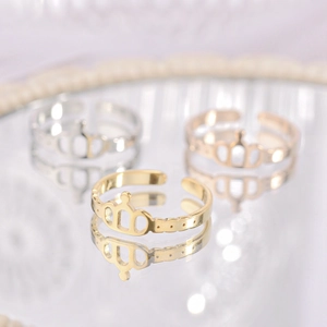 Three crown-shaped adjustable rings in gold and silver finish on reflective surface