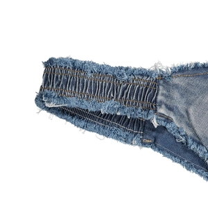 Dettaglio macro dell'elastico in vita e dei bordi sfrangiati dello short bikini in denim