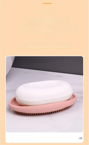 Pink silicone soap dish with integrated cleaning brush bristles on marble surface