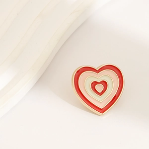 Macro shot of a heart-shaped enamel brooch with concentric red and pink stripes on white