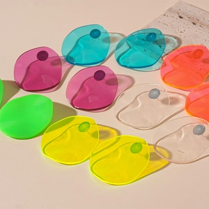 Colorful oval resin earrings in neon colors arranged on a beige background with stone