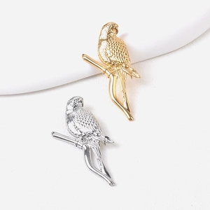 Detail of gold and silver parrot bird brooches on a branch with smooth metal finish