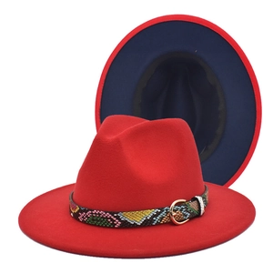 Detail of red fedora hat with navy blue brim underside and chic patterned gold buckle belt