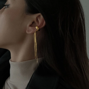 Close-up of gold tassel ear cuff earrings with elegant long metal chain fringe detail