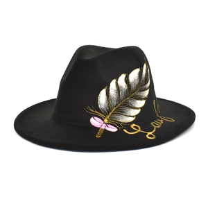 Detail of black wool fedora featuring hand-painted colorful feathers and a pink bow