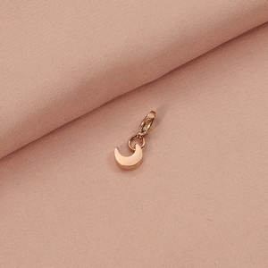 Rose gold crescent moon pendant with lobster clasp on soft pink fabric background