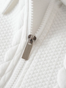 Close-up of white waffle textured fabric with silver matte metal zipper detail