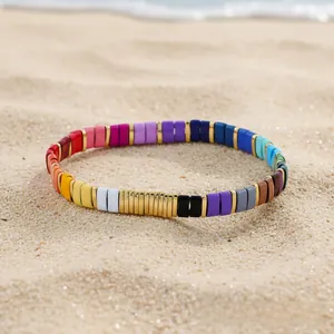 Detail of colorful enamel tile bracelets on a beach sand background with seaside vibes