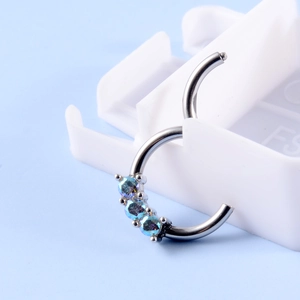 Close-up of silver steel nose hoop with three iridescent blue synthetic opals on white stand