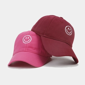 Pink and burgundy baseball caps with white smile embroidery on a white background