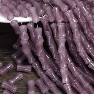 Macro shot of lilac cylinder glass beads with bamboo joint shape on dark wood surface