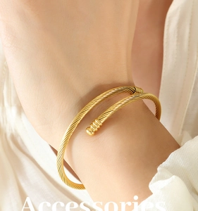 Macro shot of minimalist gold twisted rope open bangle with sphere detail on wrist