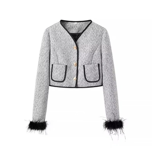 Detail of grey tweed jacket featuring golden buttons and black feather cuffs accents