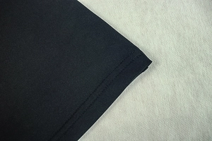 Detailed close-up of double-needle stitching on the hem of a black knitted dress