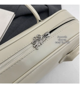 Close-up of retro silver metal zipper with artistic TR letter detail on beige leather bag