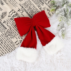 Red velvet Christmas bow with white faux fur trim on festive winter background