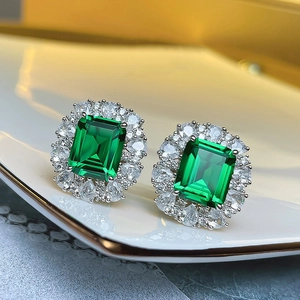 Detailed view of emerald cut green gemstone halo stud earrings with sparkling silver finish
