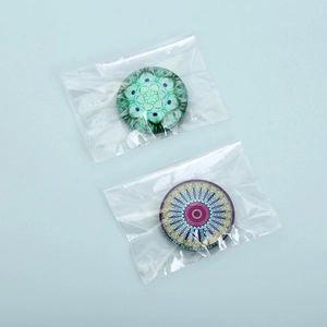Detail of round mandala glass fridge magnets with intricate patterns in small plastic bags