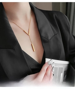 Close-up of elegant V-shaped Y-necklace in gold finish on a black blazer background