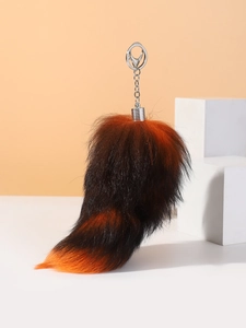 Macro shot of fluffy orange and brown faux fox tail keychain with silver metal clip