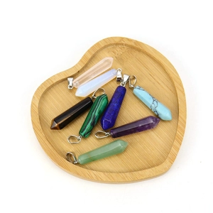 Macro shot of assorted hexagonal crystal stone pendants in a heart-shaped wooden tray