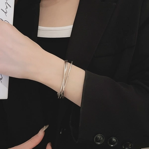 Polished silver wave crossover cuff bracelet styled on a model wrist with a black blazer